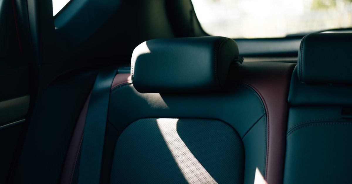 A clean black seat inside of a truck. Sunlight is shining through the window, partially illuminating