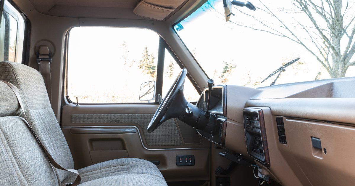 A pickup truck interior featuring beige seats and a beige dashboard. The truck is parked outside during the day.