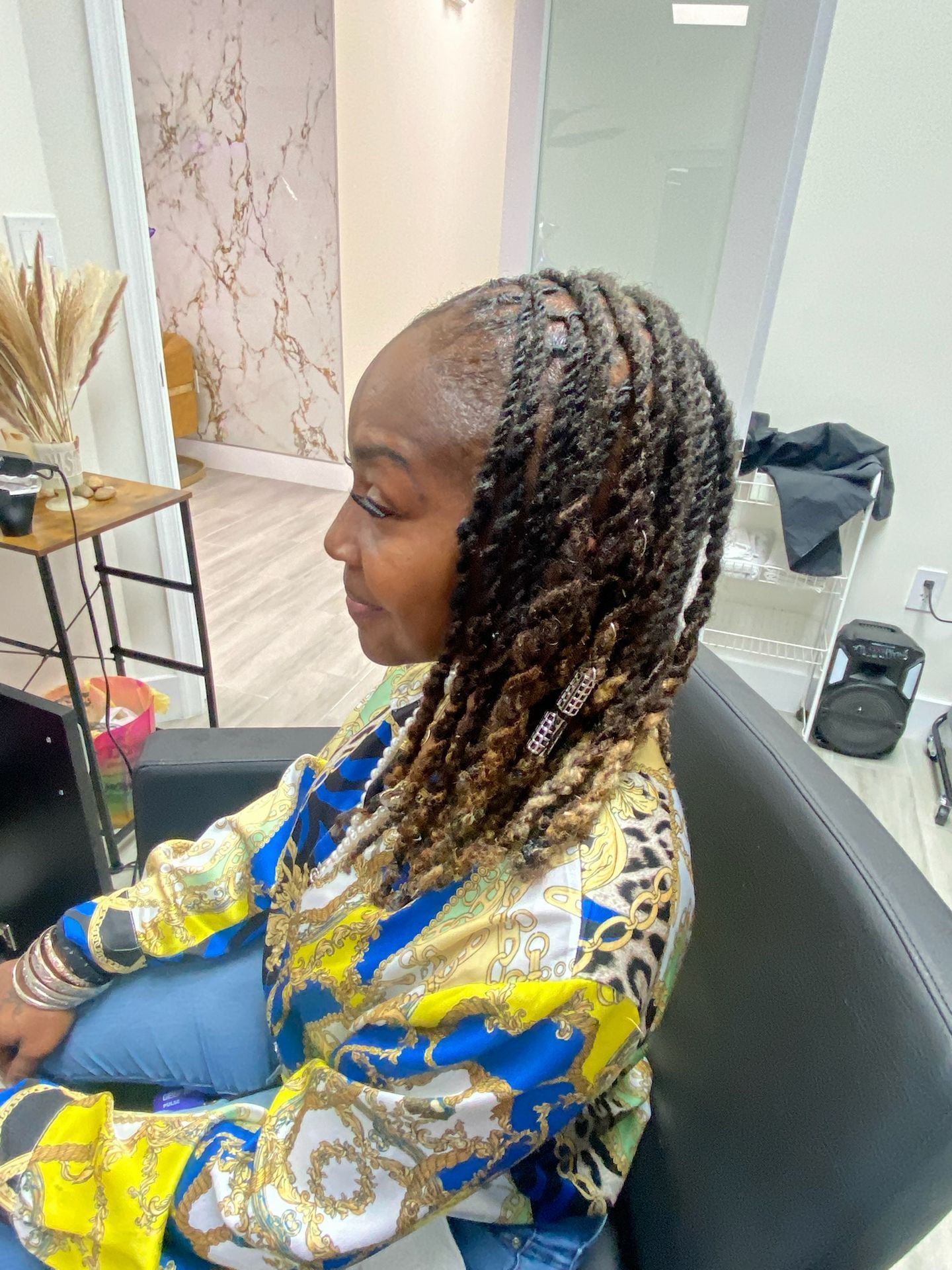 Woman with brown and blonde twists hairstyle sits in a salon chair.