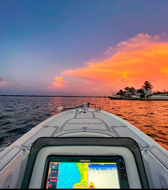 Boat on water with sunset sky, navigation screen visible.