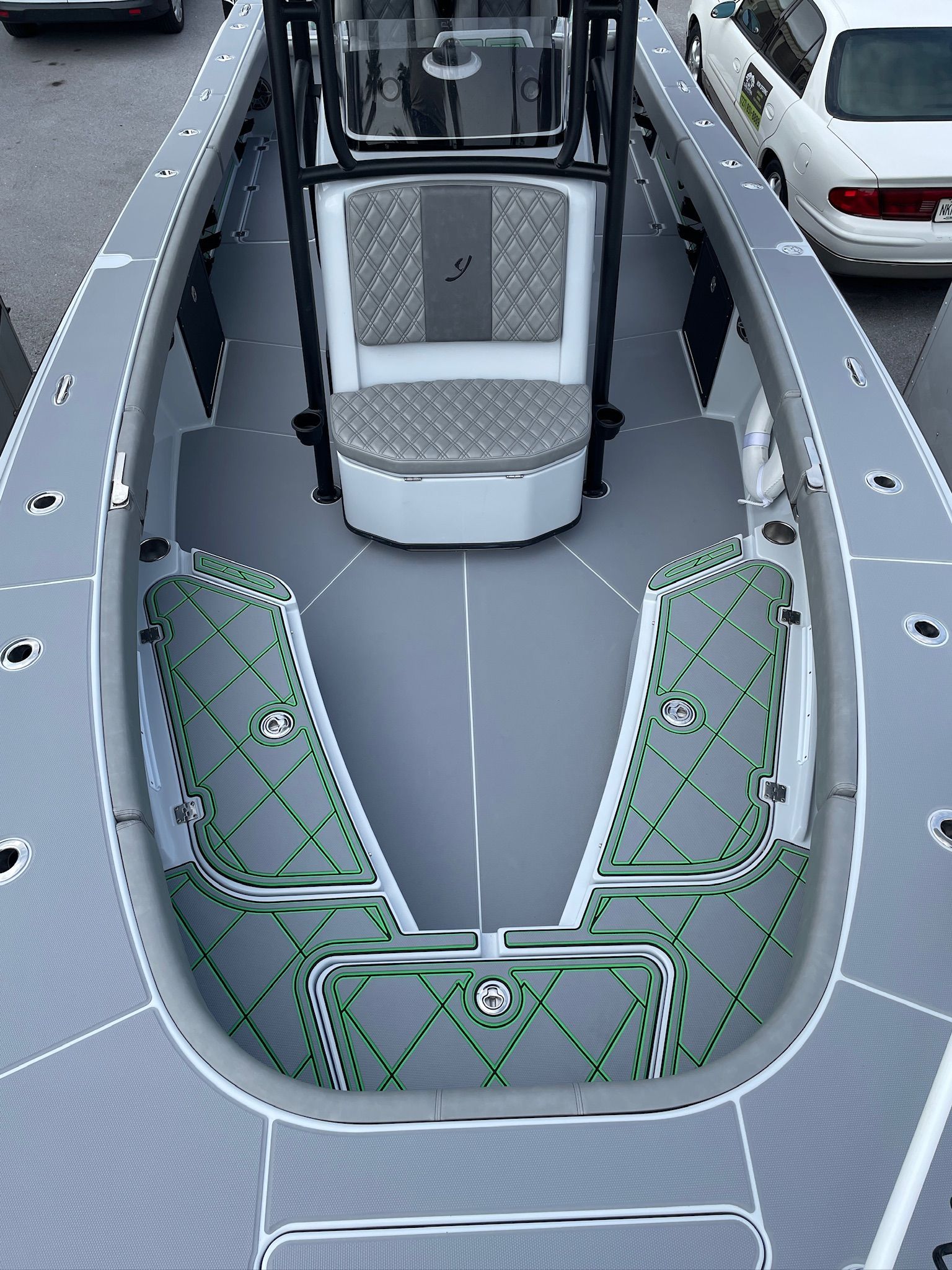 View from above of a gray boat deck with green accents, center console, and padded seating.