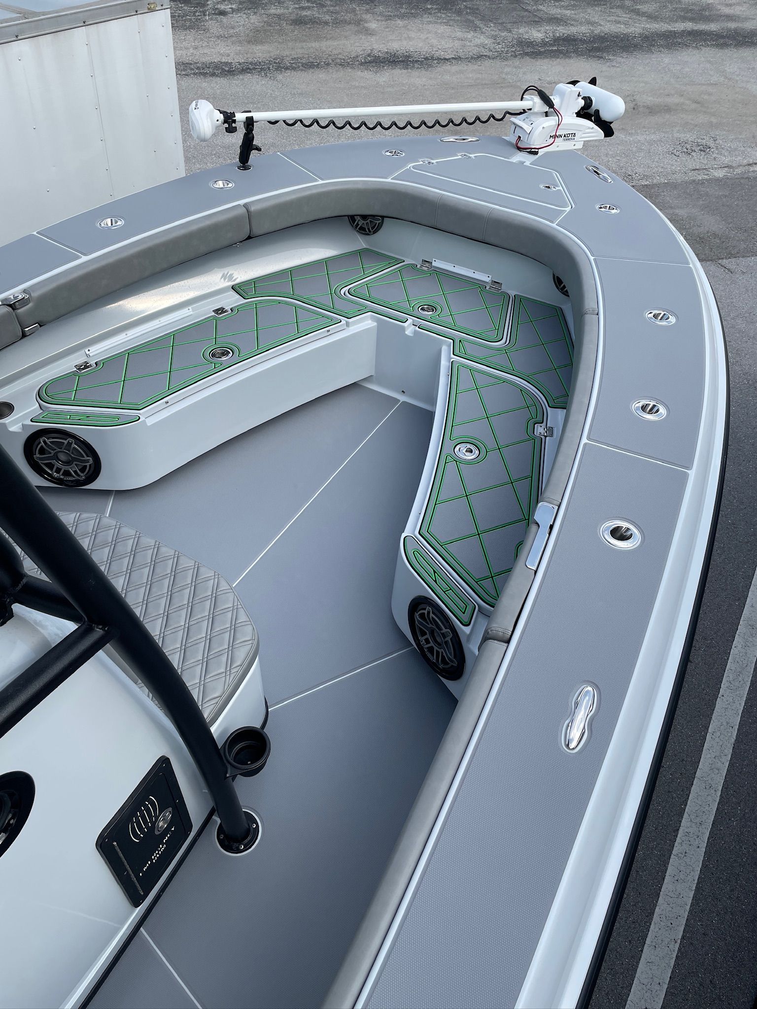Gray and white fishing boat with green accents on the seats, shot from a high angle.