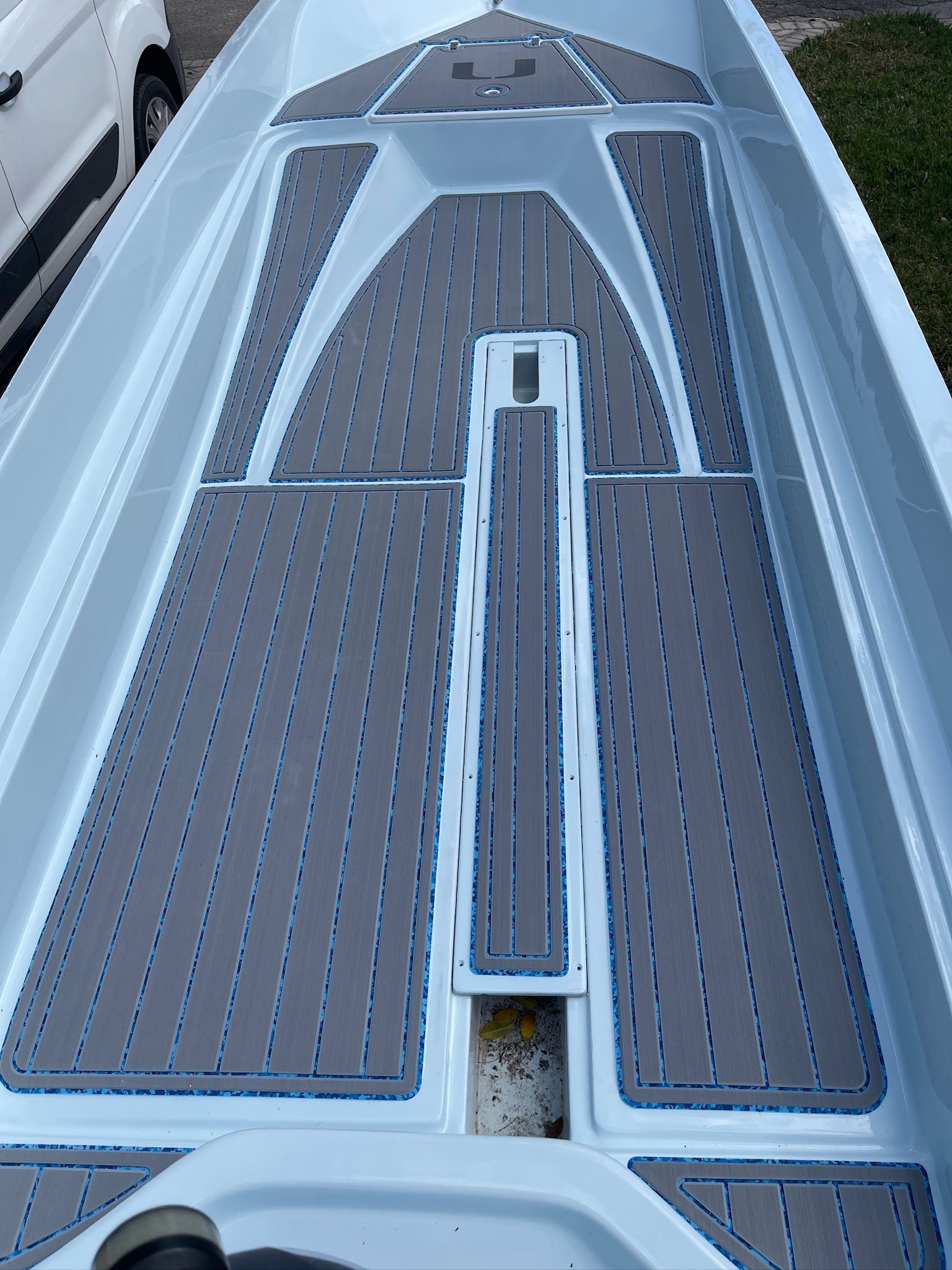 Interior of a light-colored boat with gray non-slip flooring and blue accents.