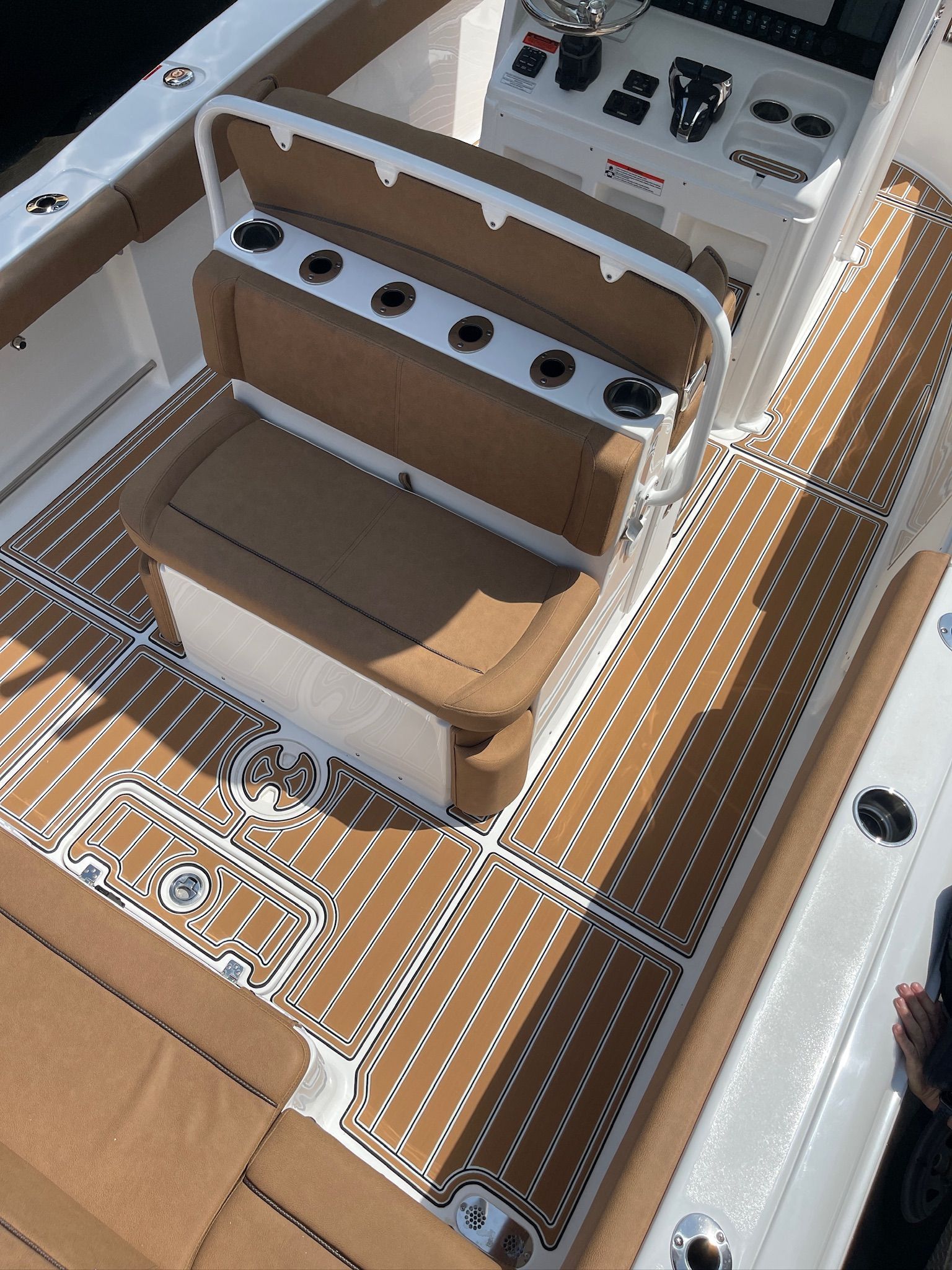 Boat deck with brown and white flooring, a brown seat, and cup holders.