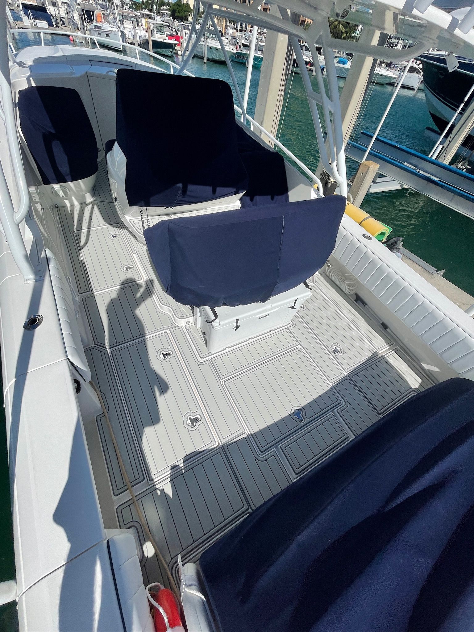 Overhead view of a boat deck with seats covered in navy blue. A marina is visible in the background.