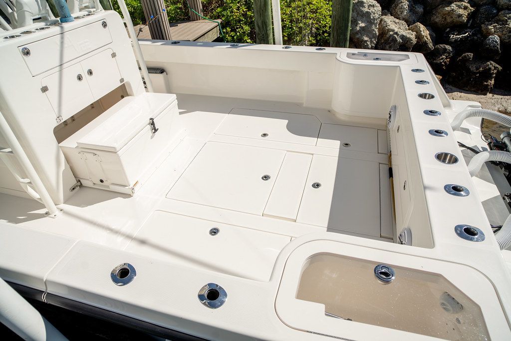 White boat deck with fishing rod holders, a storage box, and access hatches.