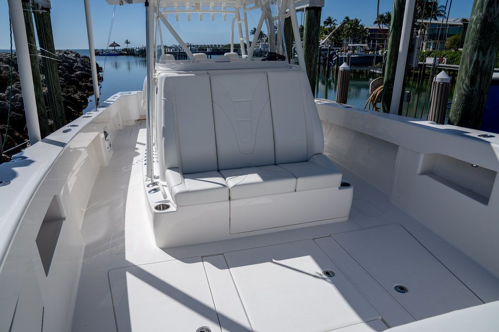 White boat deck with cushioned seating and a dock in the background.