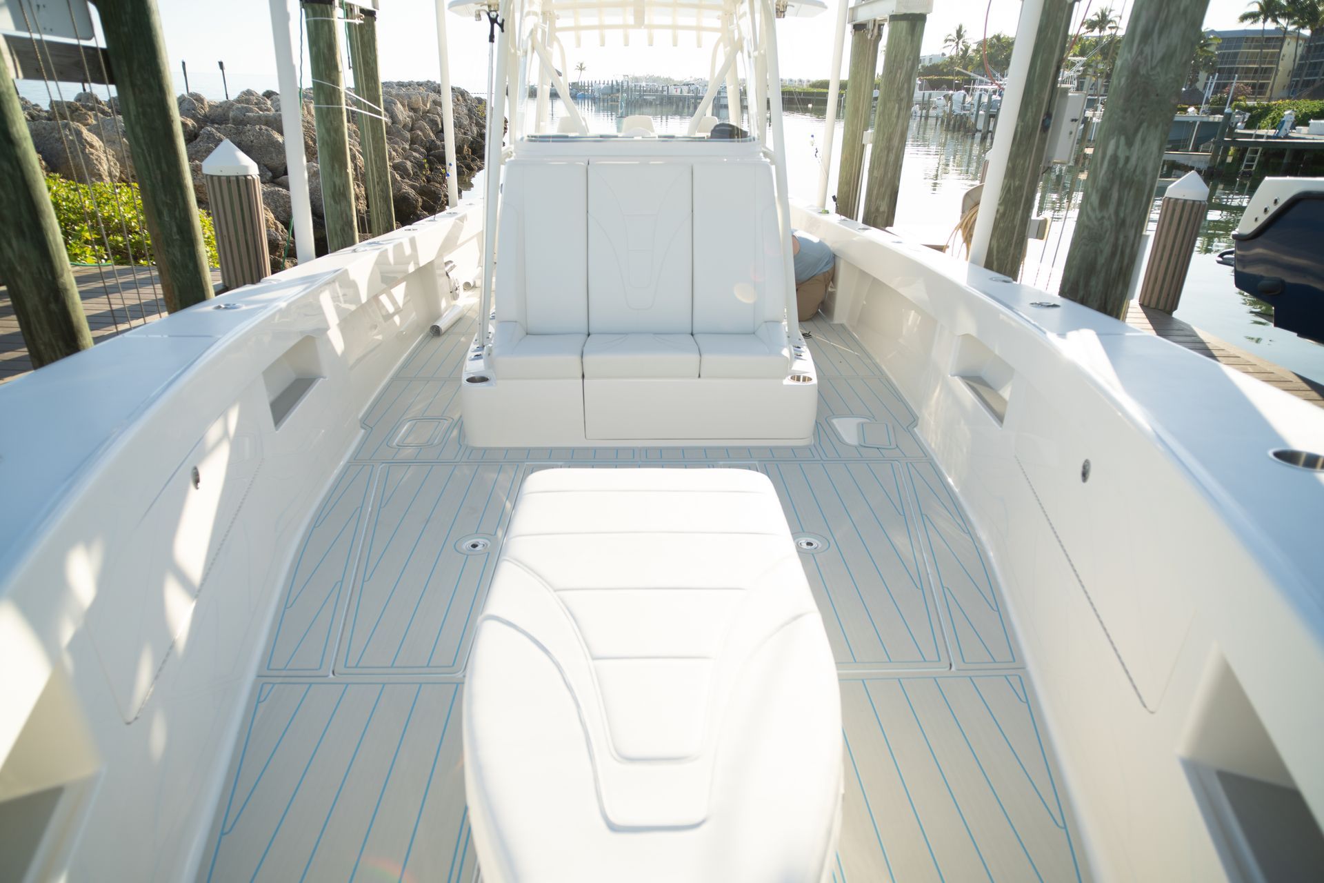 Boat deck with white seats and a large engine. Wood pilings and a waterway are visible.
