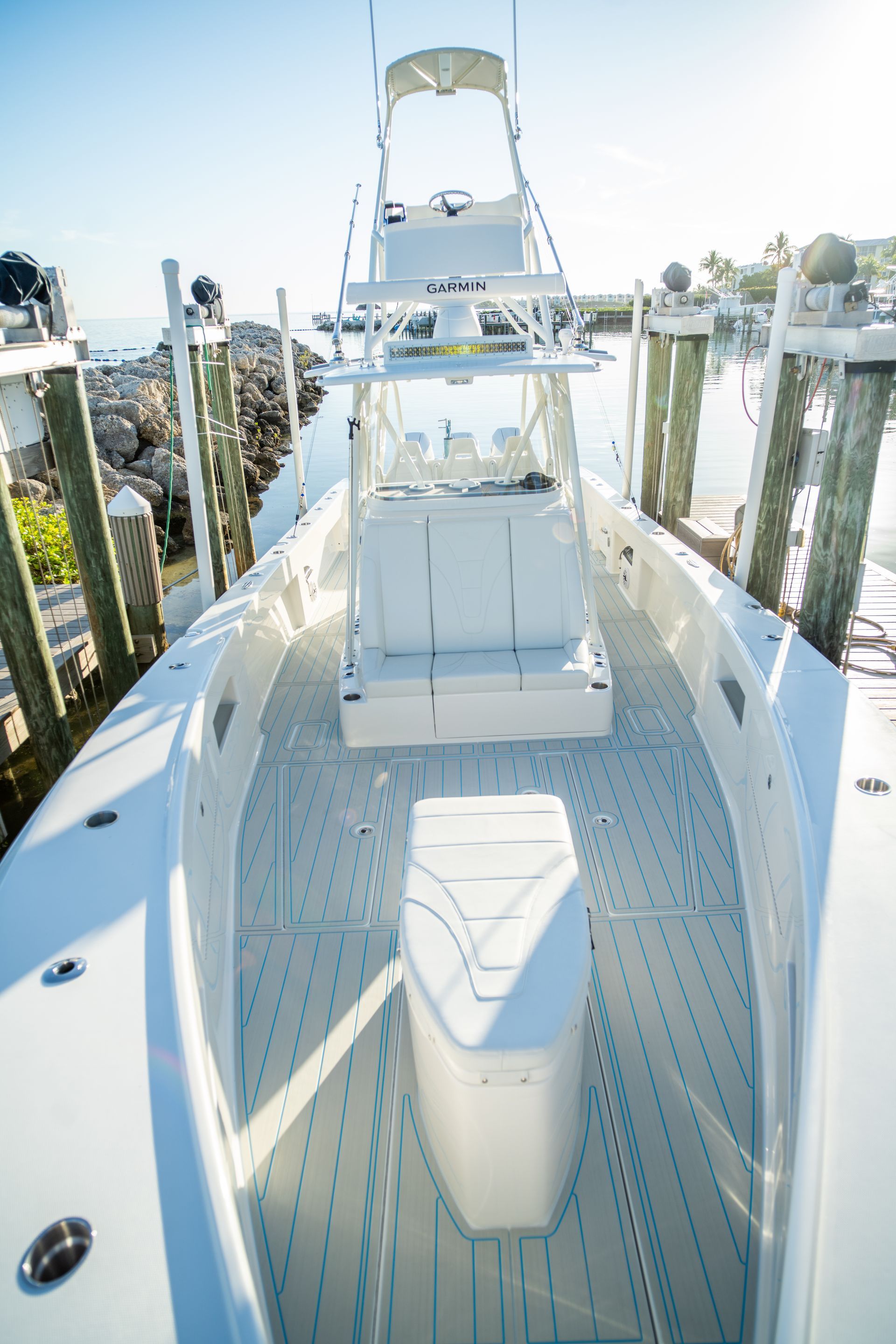 White fishing boat with a high center console, docked near wooden posts.