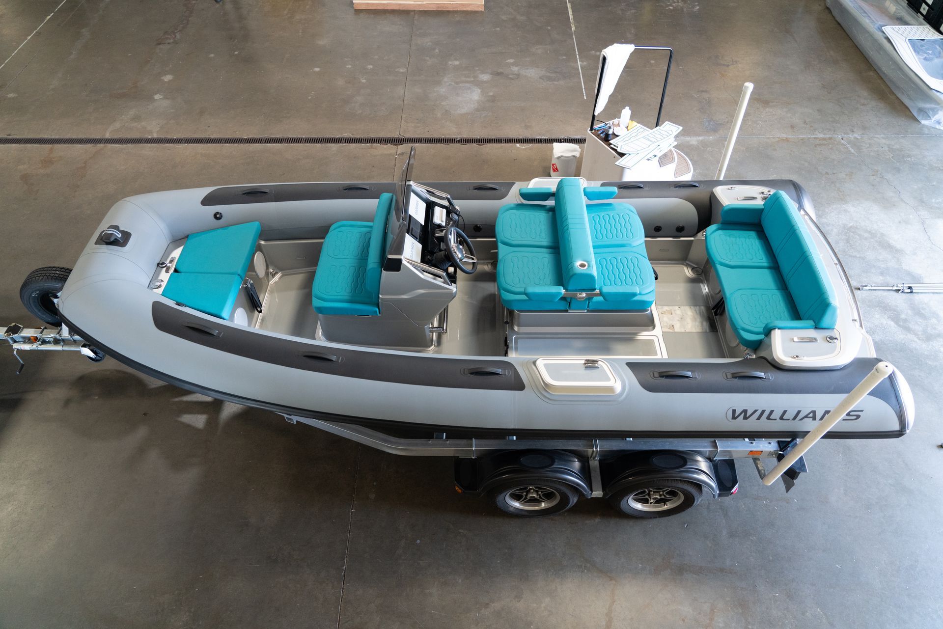 Gray inflatable boat with teal cushions on a trailer.