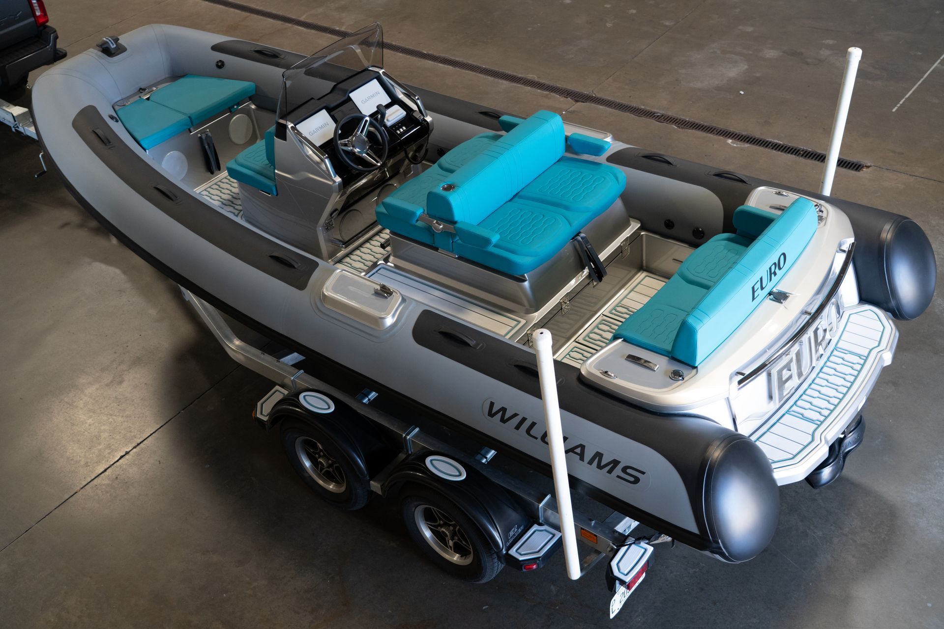 A gray Williams RIB boat on a trailer, with teal seating.