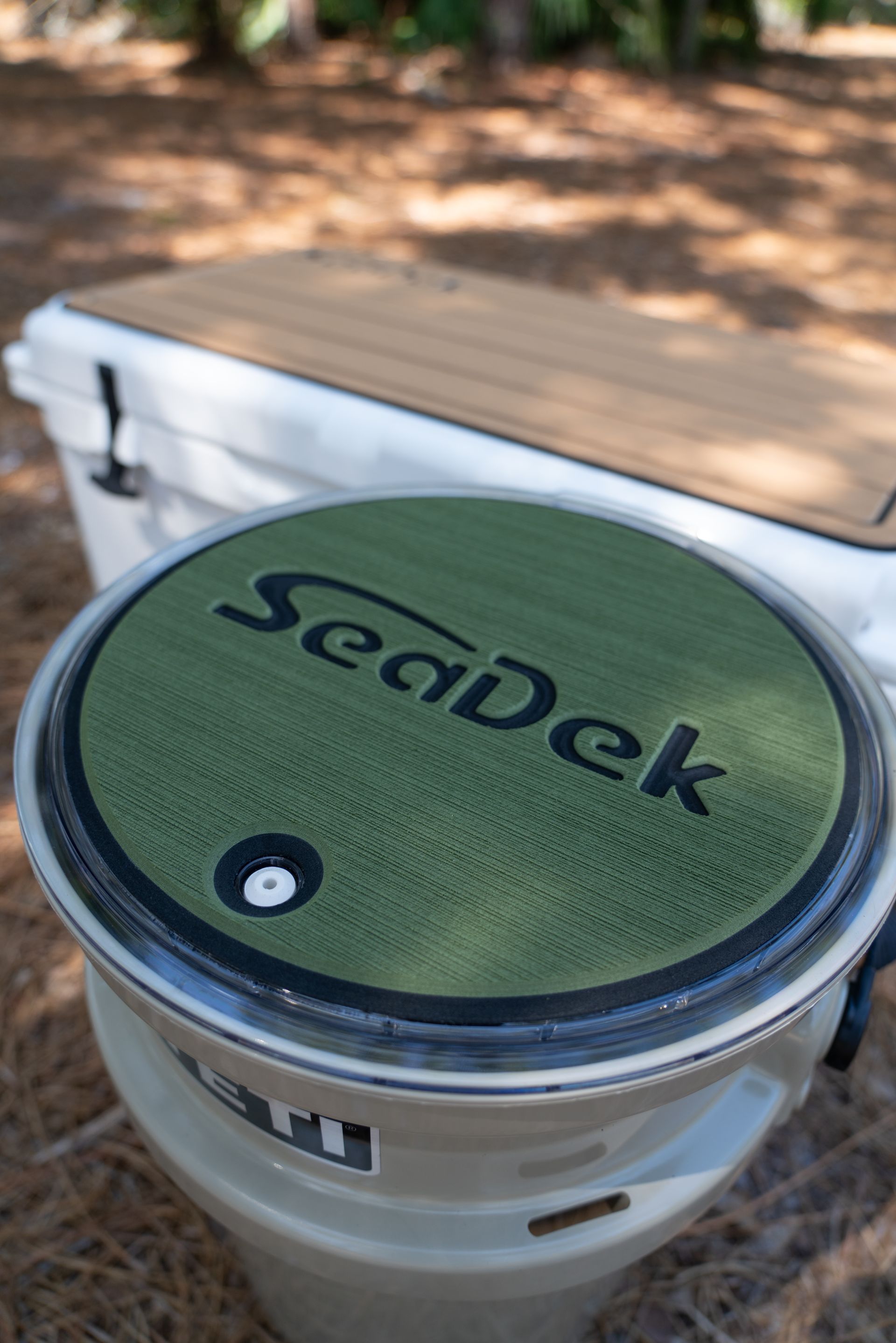 Two coolers with SeaDek lids. One lid is green with black text. A second cooler is in the background.