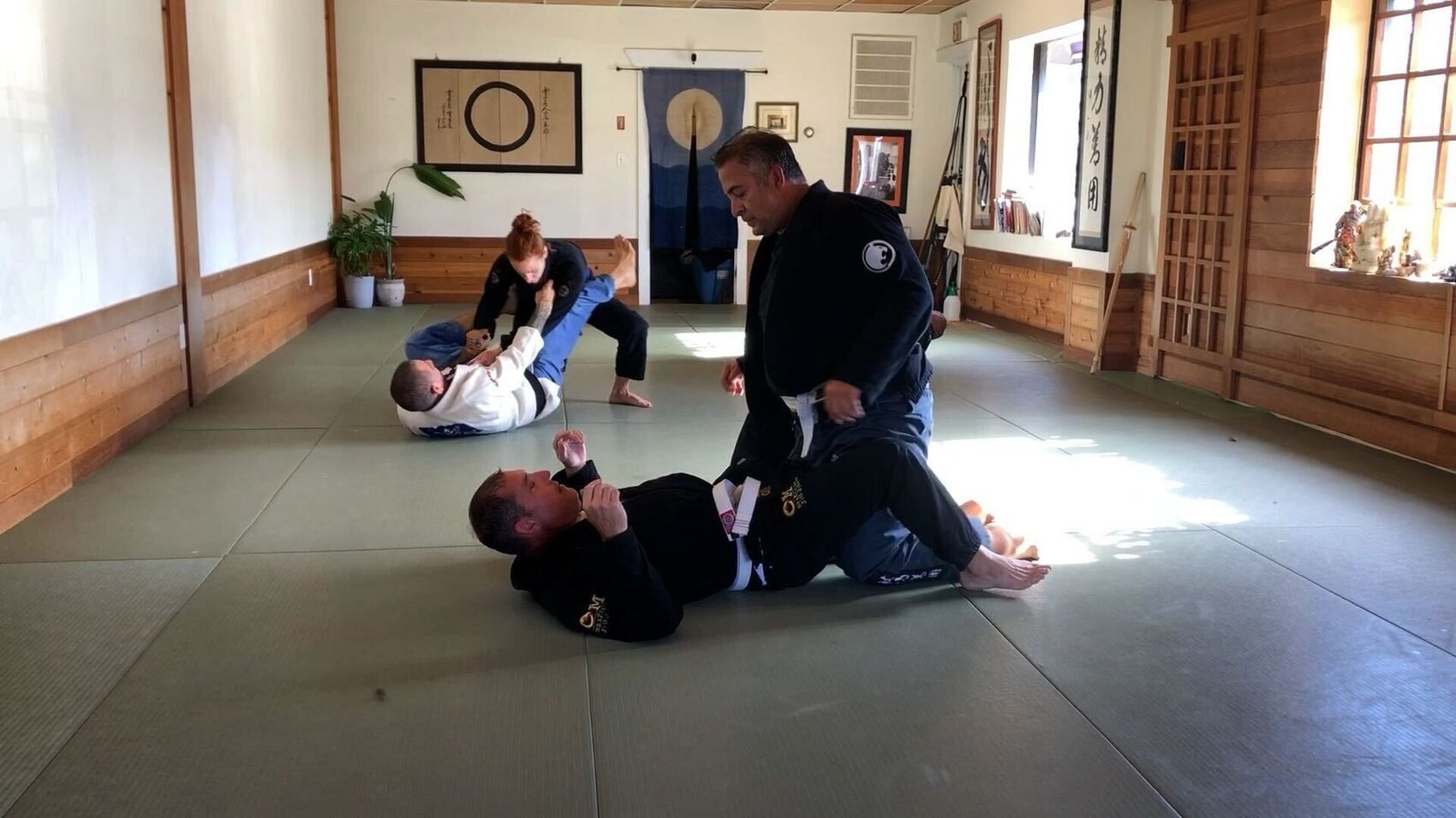 Adults rolling in class at OM Brazilian Jiu JItsu & Judo in Northport, NY, building calm strength under pressure.