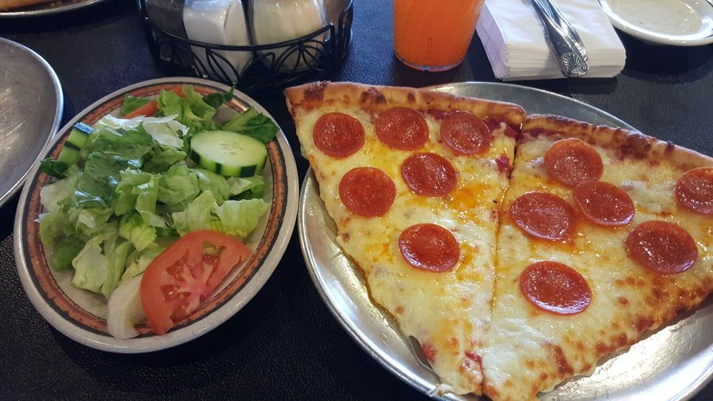 a slice of pepperoni pizza is on a plate next to a salad .