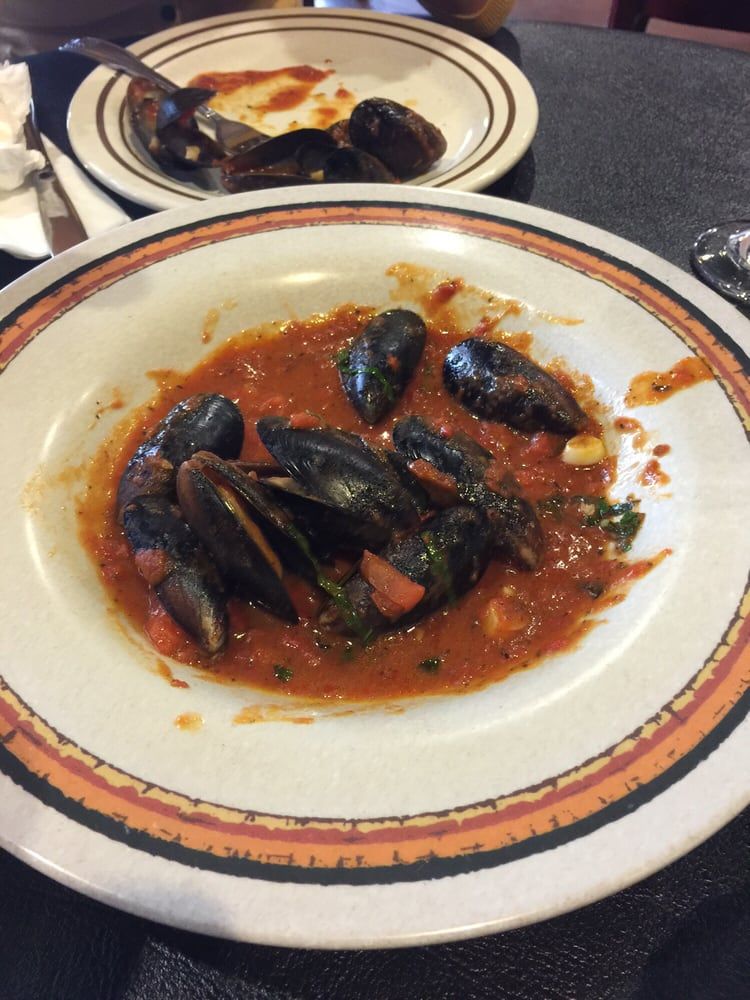 a plate of mussels in tomato sauce on a table