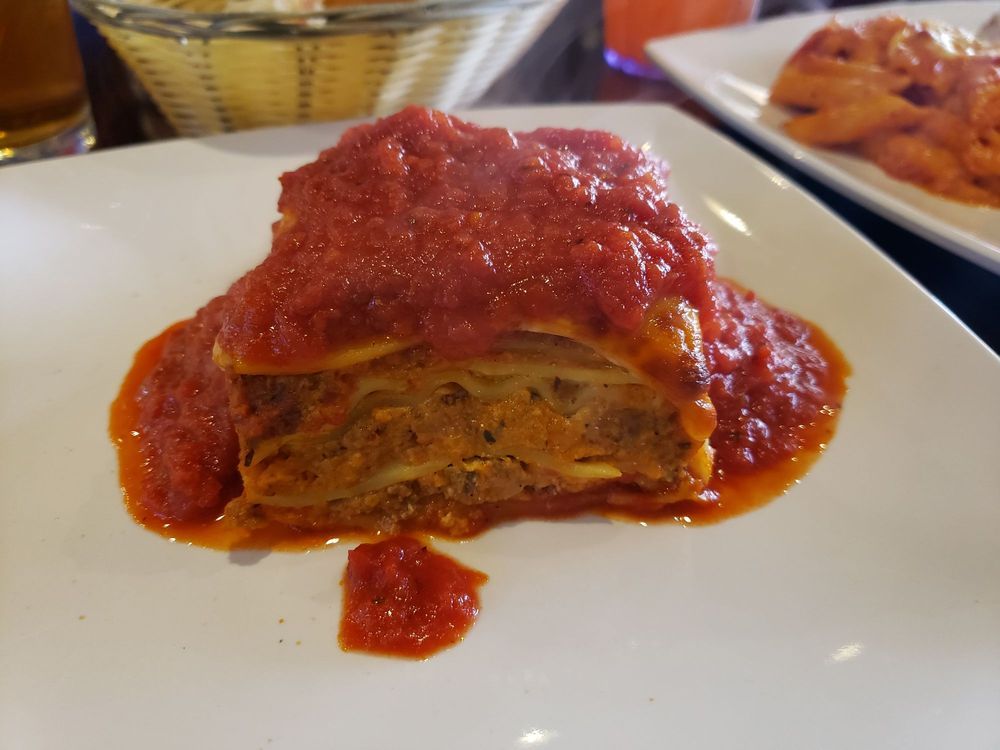 a slice of lasagna with tomato sauce on a white plate