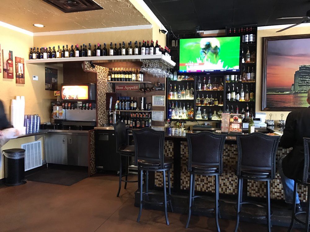 a man is sitting at a bar in a restaurant watching a football game .