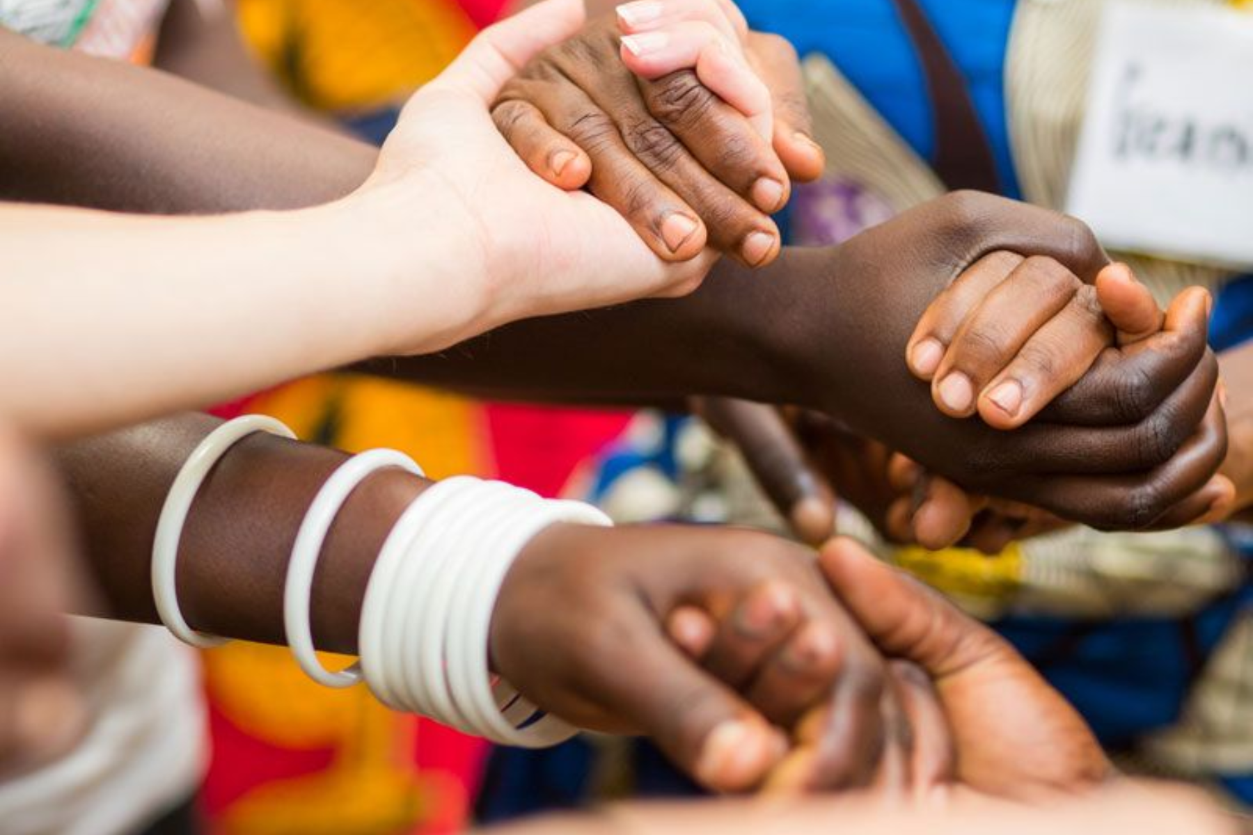 Hands of various skin tones clasped together.