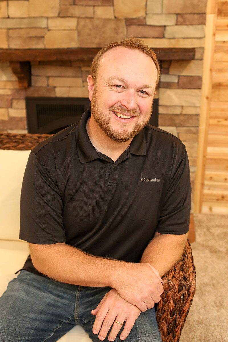 Pastor Chad Farber sitting in front of a stone fireplace.