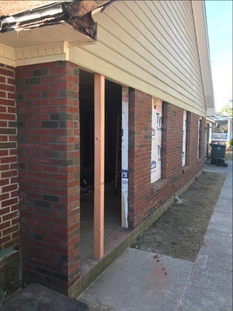 A brick building with a white siding is being remodeled