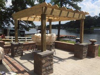 A wooden pergola is being built on a patio overlooking a lake