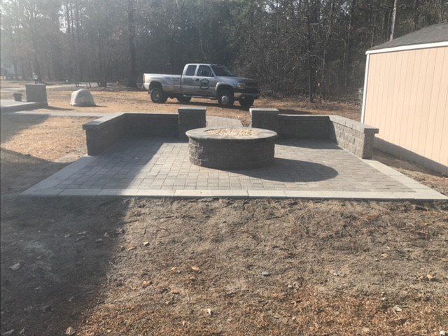 A truck is parked next to a fire pit on a patio.
