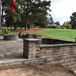 A brick wall surrounding a patio with a view of a golf course.