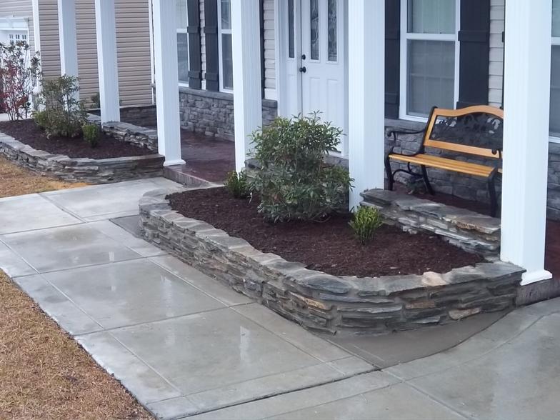 A concrete walkway with a bench in front of a house