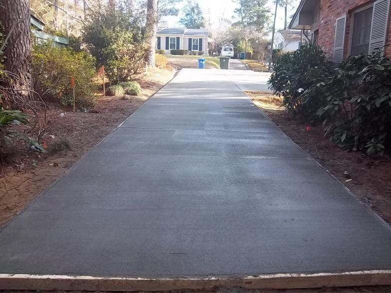 A concrete driveway leading to a house in a residential area