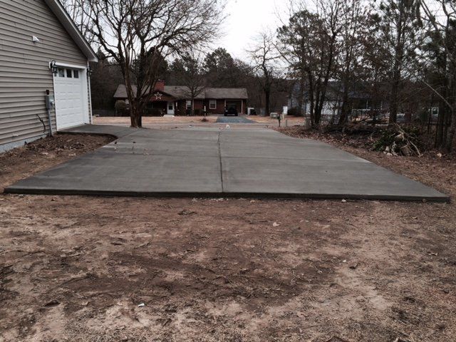 A concrete driveway with a house in the background