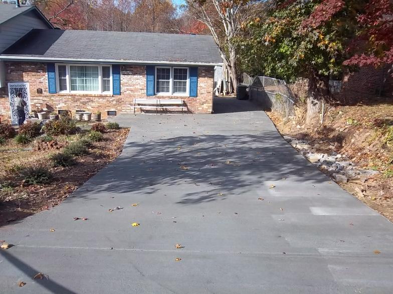 A driveway leading to a brick house with blue shutters