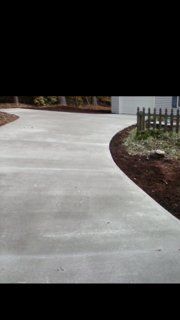 A concrete driveway with a wooden fence in the background.