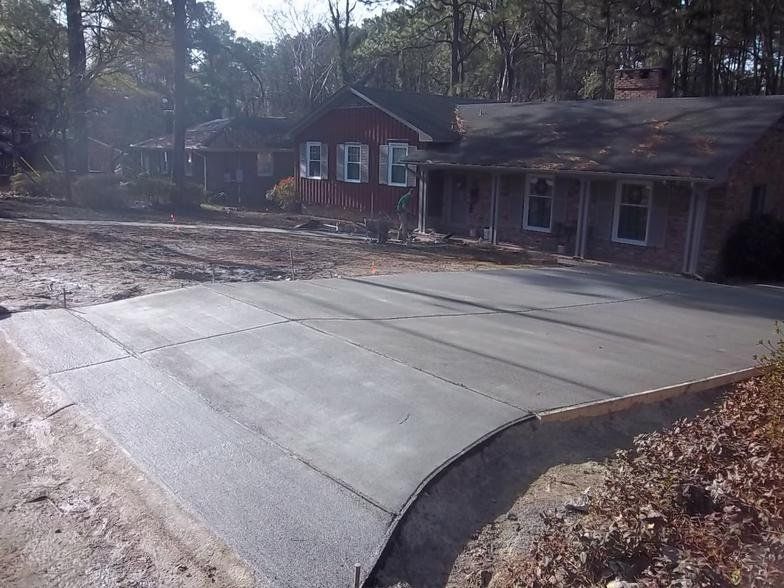 A brick house with a concrete driveway in front of it