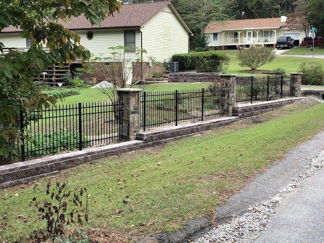 A fence surrounds a lush green yard in front of a house.