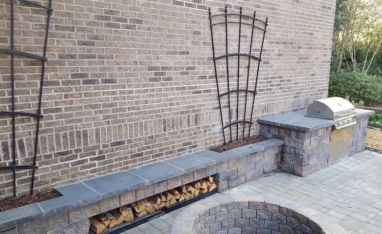 There is a fire pit in front of a brick wall.