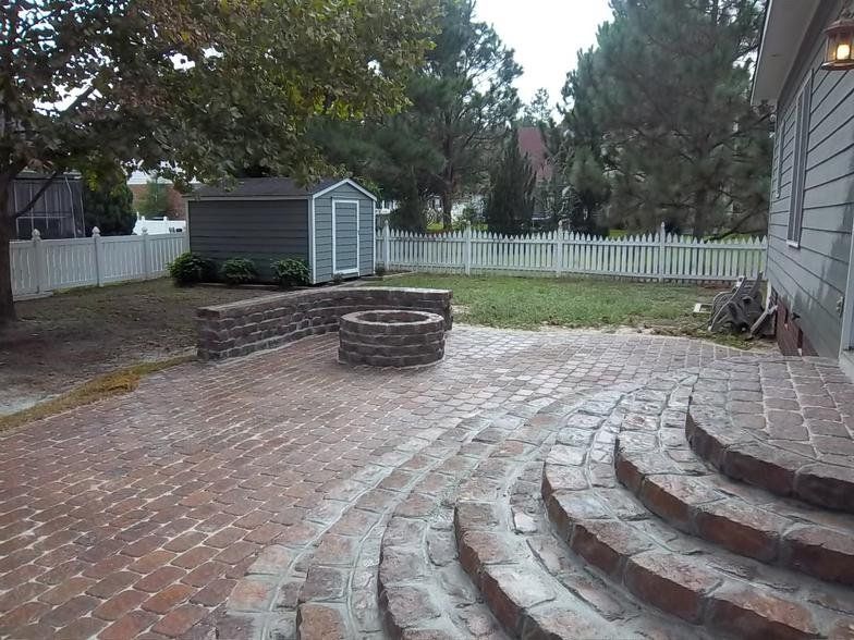 A brick patio with stairs and a fire pit in the middle