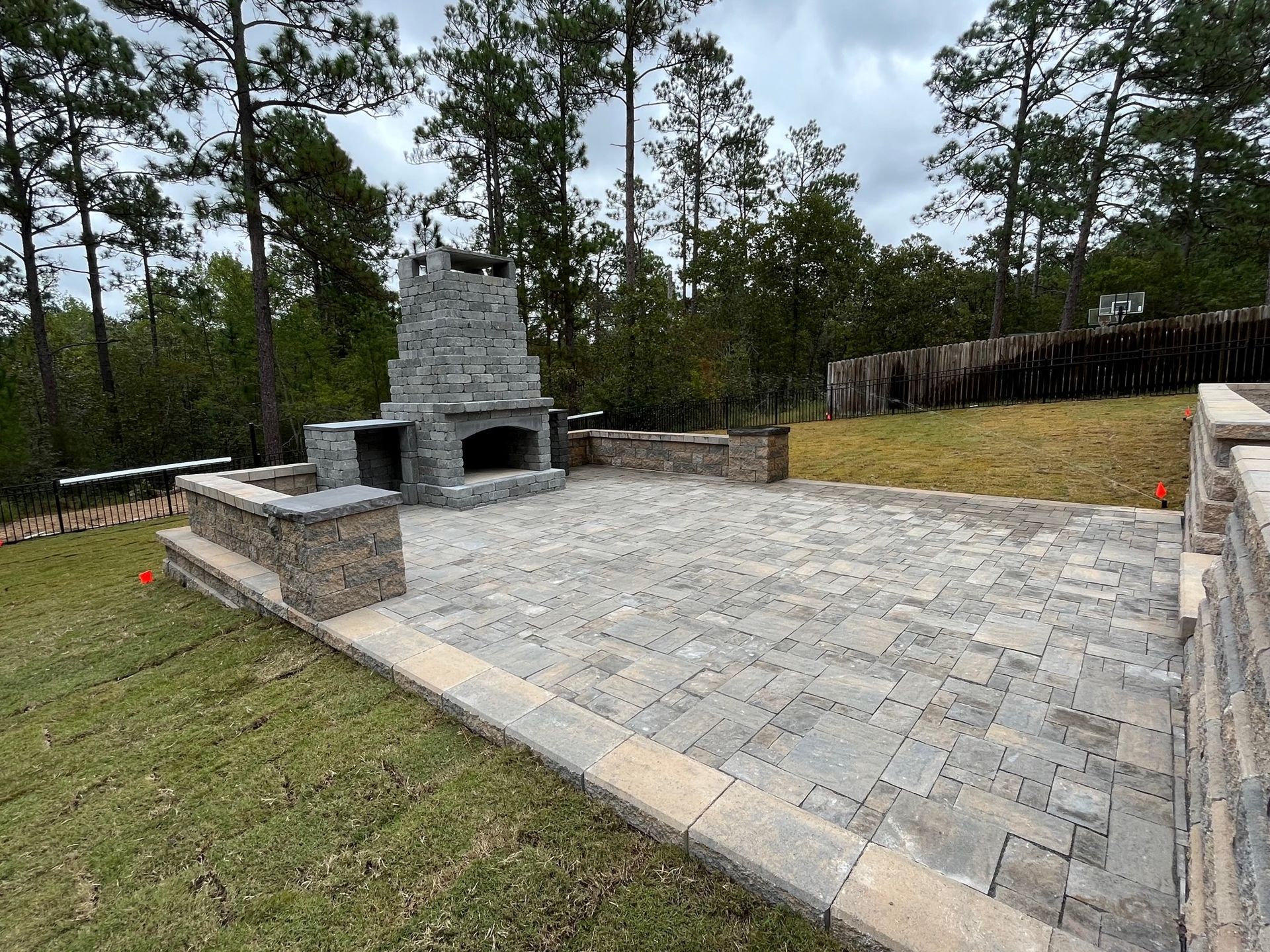 A patio with a fireplace and trees in the background.
