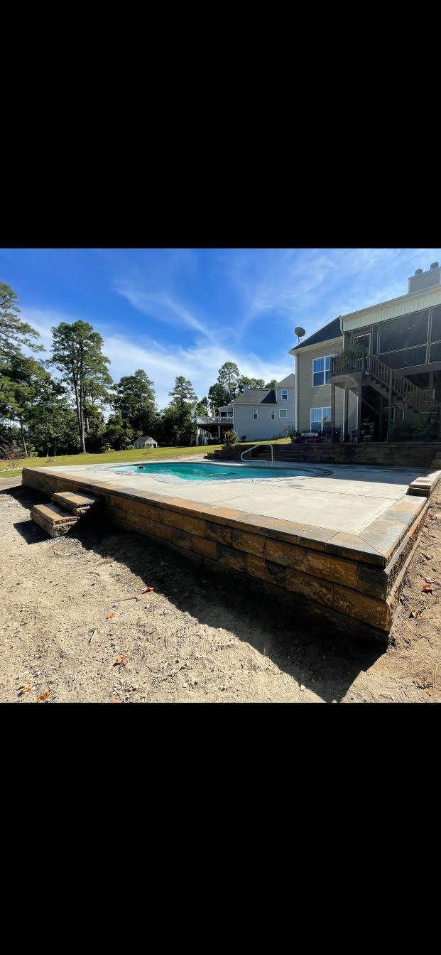 There is a large swimming pool in the backyard of a house.