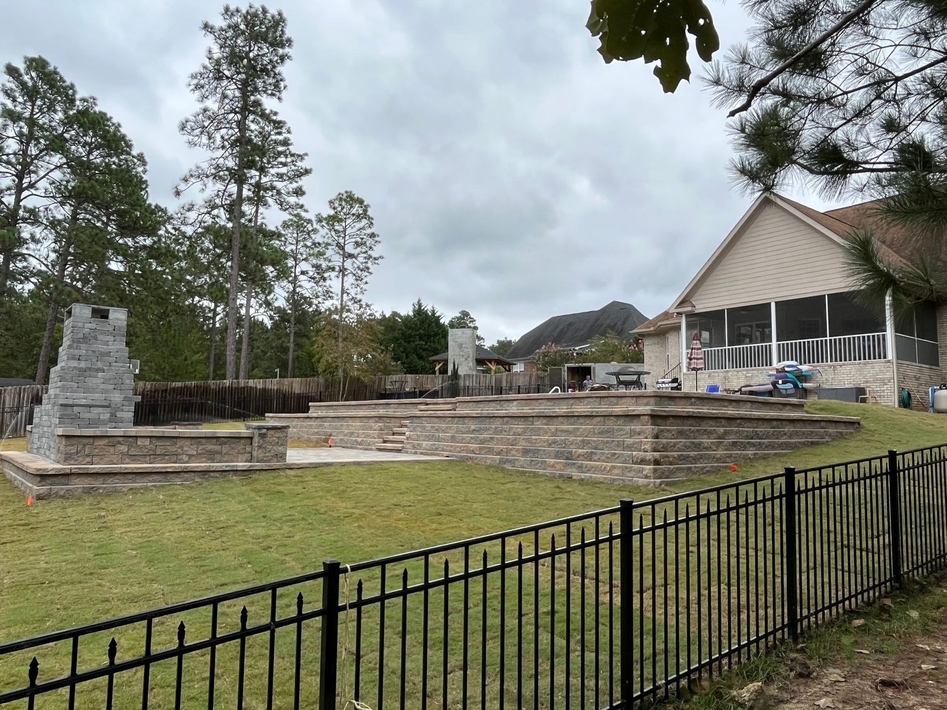 A fence surrounds a large yard with a house in the background.