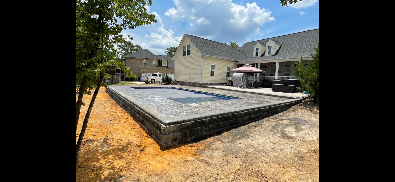 A large swimming pool is being built in the backyard of a house.