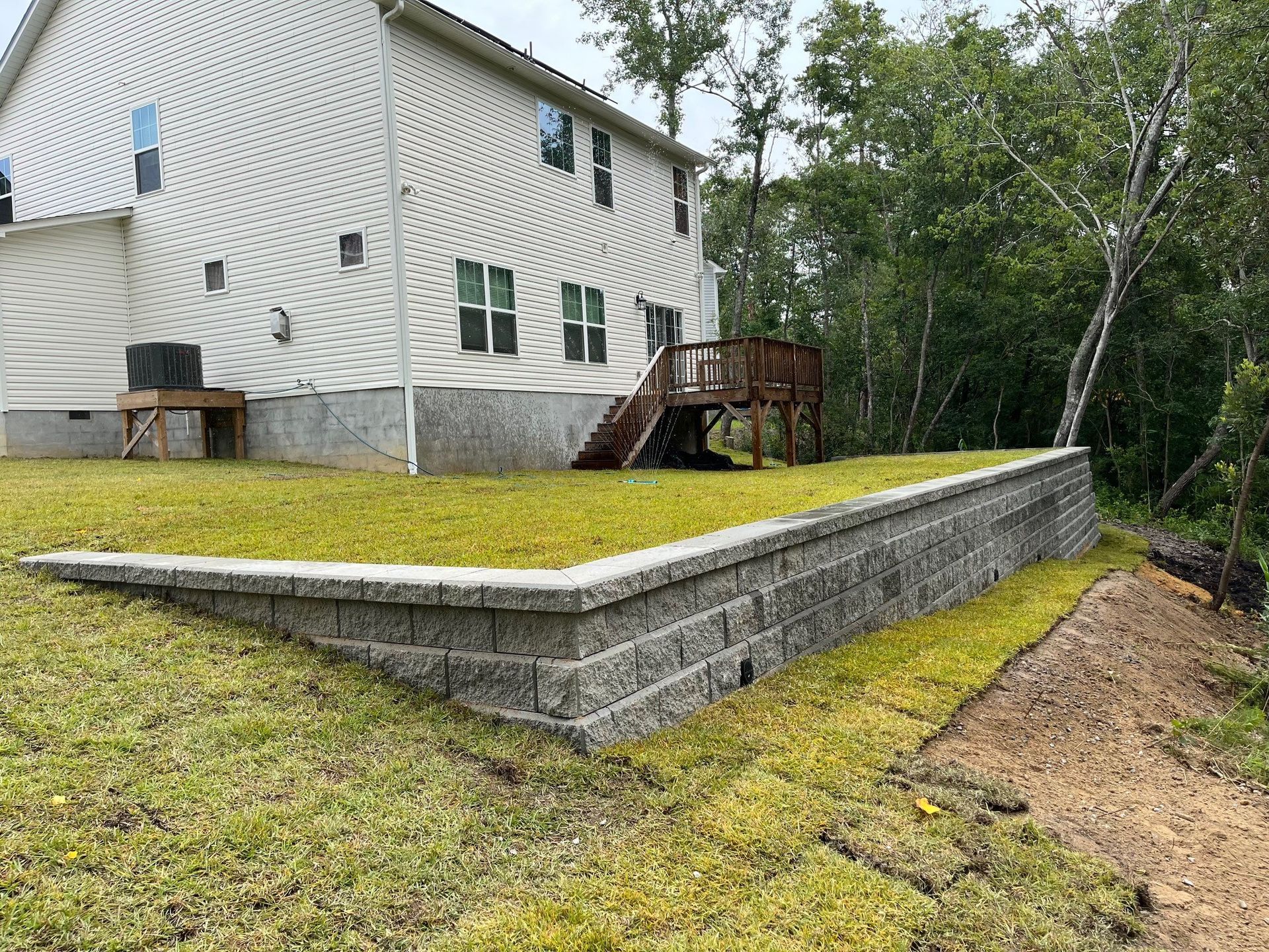 A house with a deck and a brick wall in front of it.