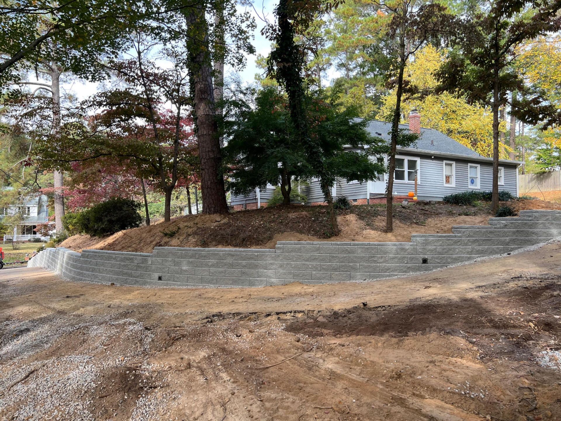 A house is sitting on top of a dirt hill surrounded by trees.
