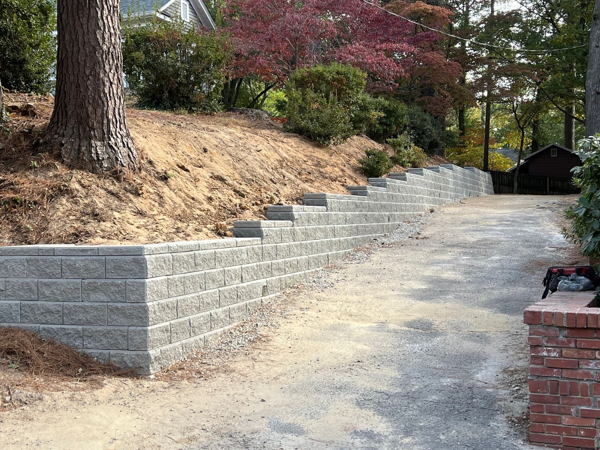 A brick wall is being built on the side of a dirt road.