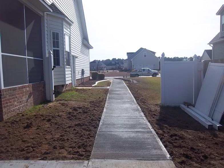 A concrete walkway leading to a house with a screened in porch