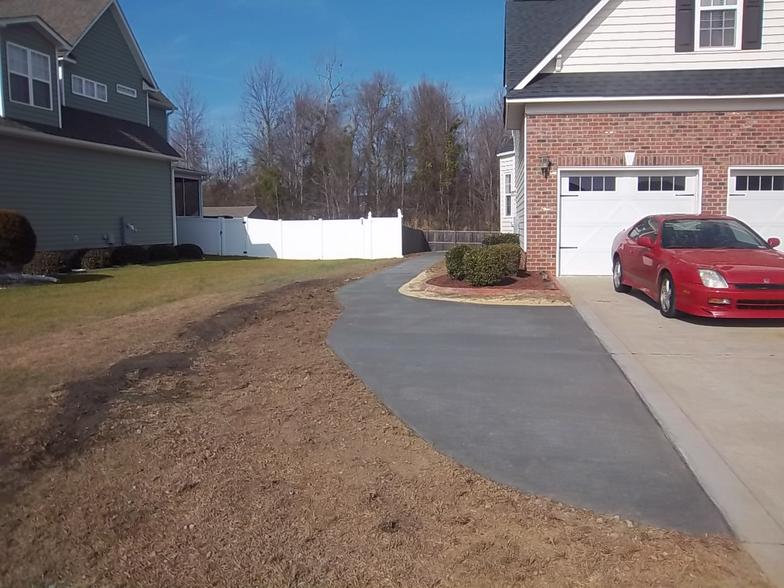 A red car is parked in front of a brick house