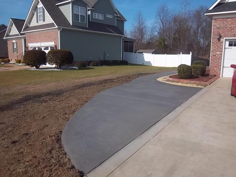 A brick house with a concrete walkway leading to it