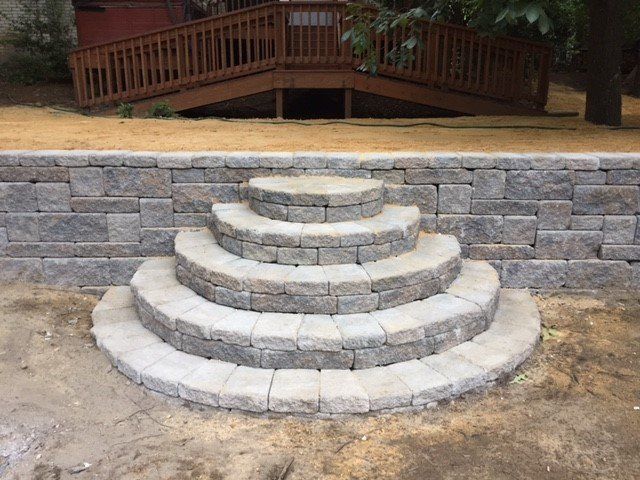 A set of stairs built into a retaining wall next to a wooden deck.