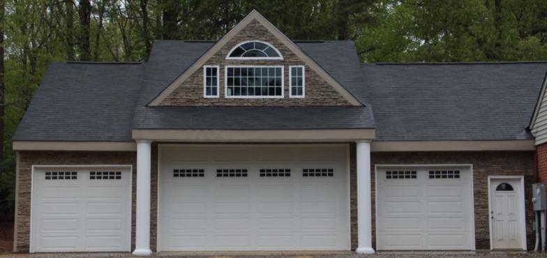A house with three garage doors and a window on top