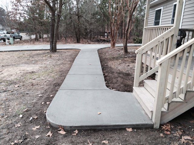 A concrete walkway leading to a house with stairs