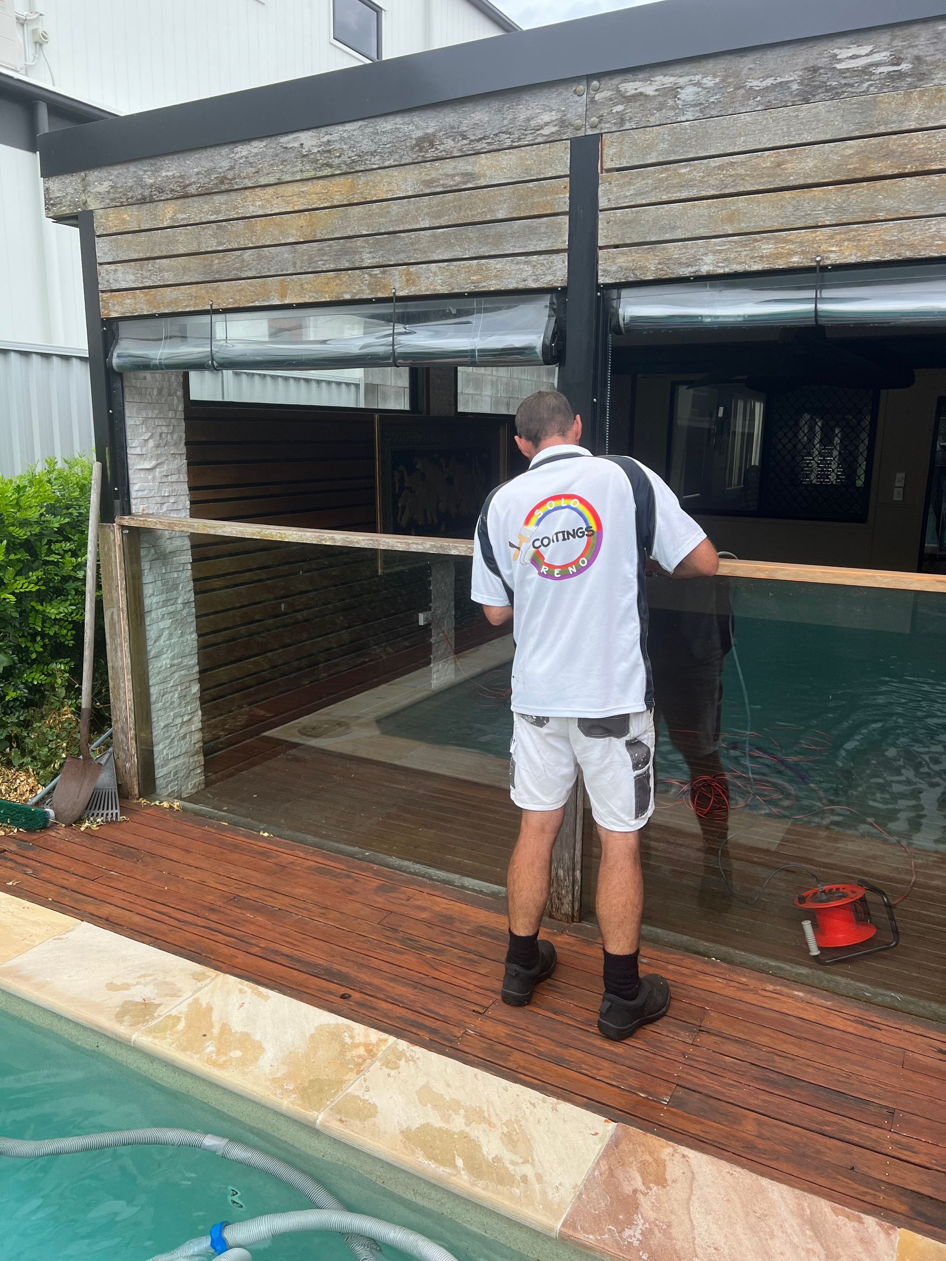 A Man Sanding A Glass Pool Fence — Solo Reno Coatings In Gold Coast, QLD